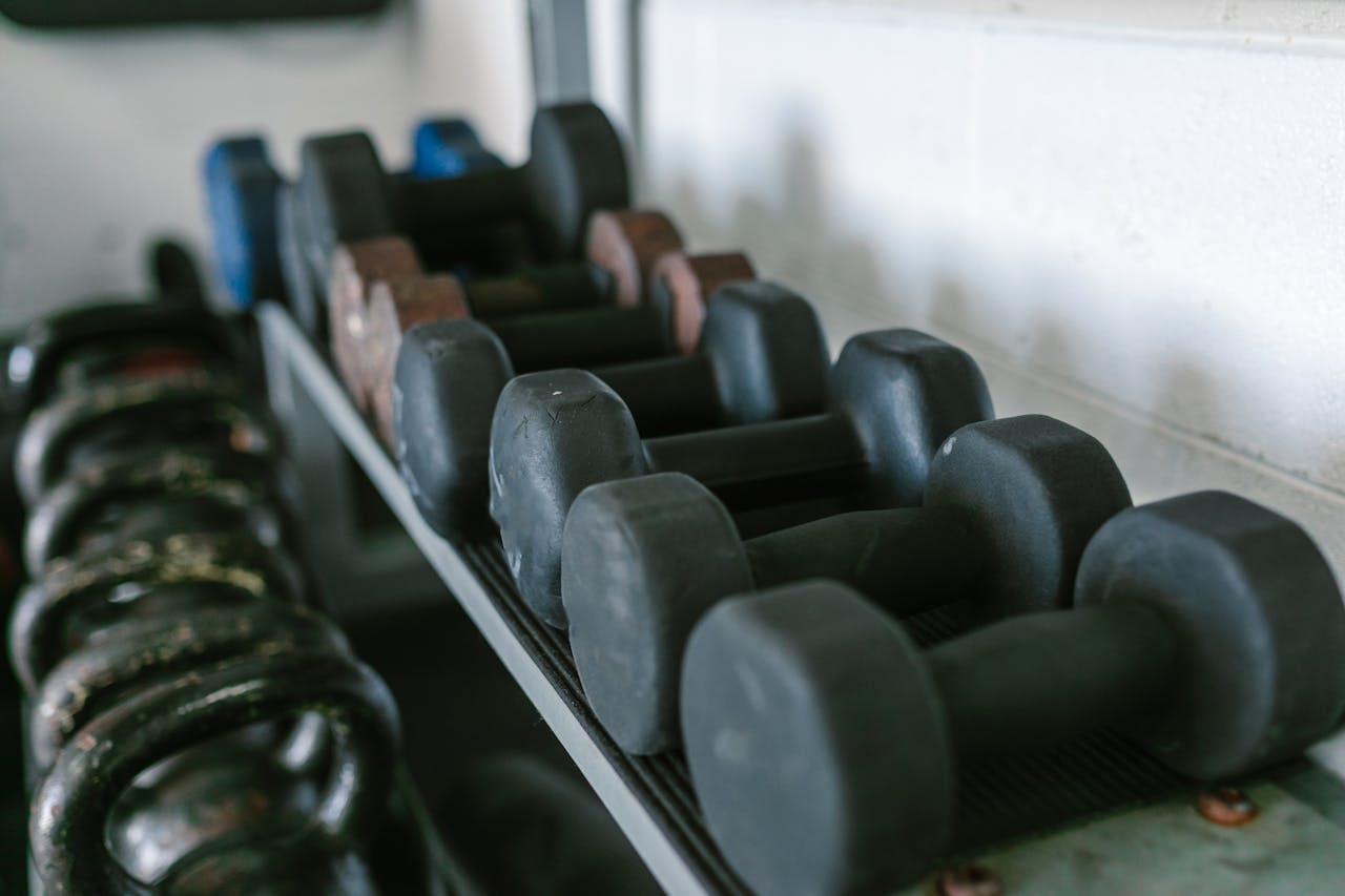 Neatly arranged dumbbells and kettlebells on racks in a gym environment.